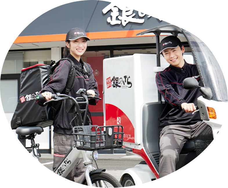 店舗前で配達用バイクと並ぶデリバリースタッフ
