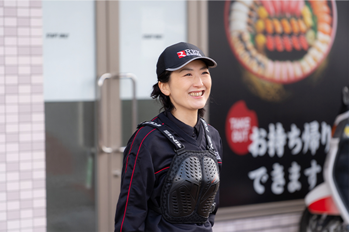 店舗前で笑顔を見せるデリバリースタッフ