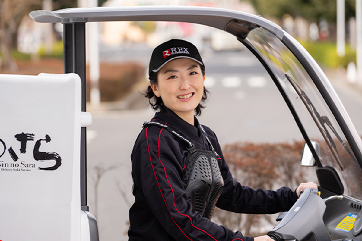 配達用車両のそばで笑顔を見せるデリバリースタッフ