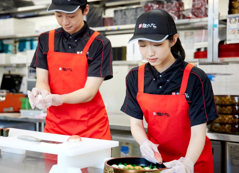厨房で先輩スタッフと調理作業をするYさん