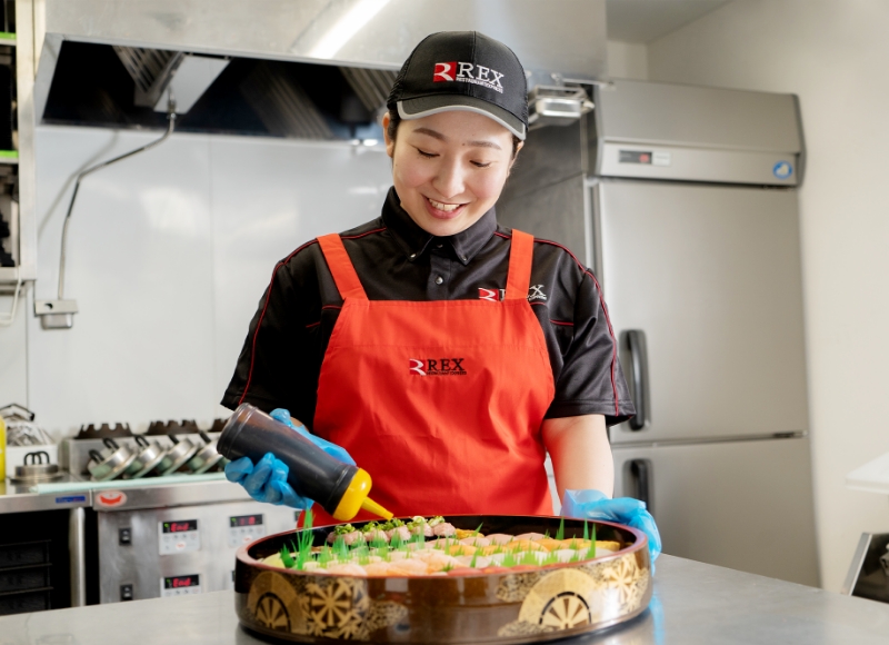 料理に調味料を入れるSさん
