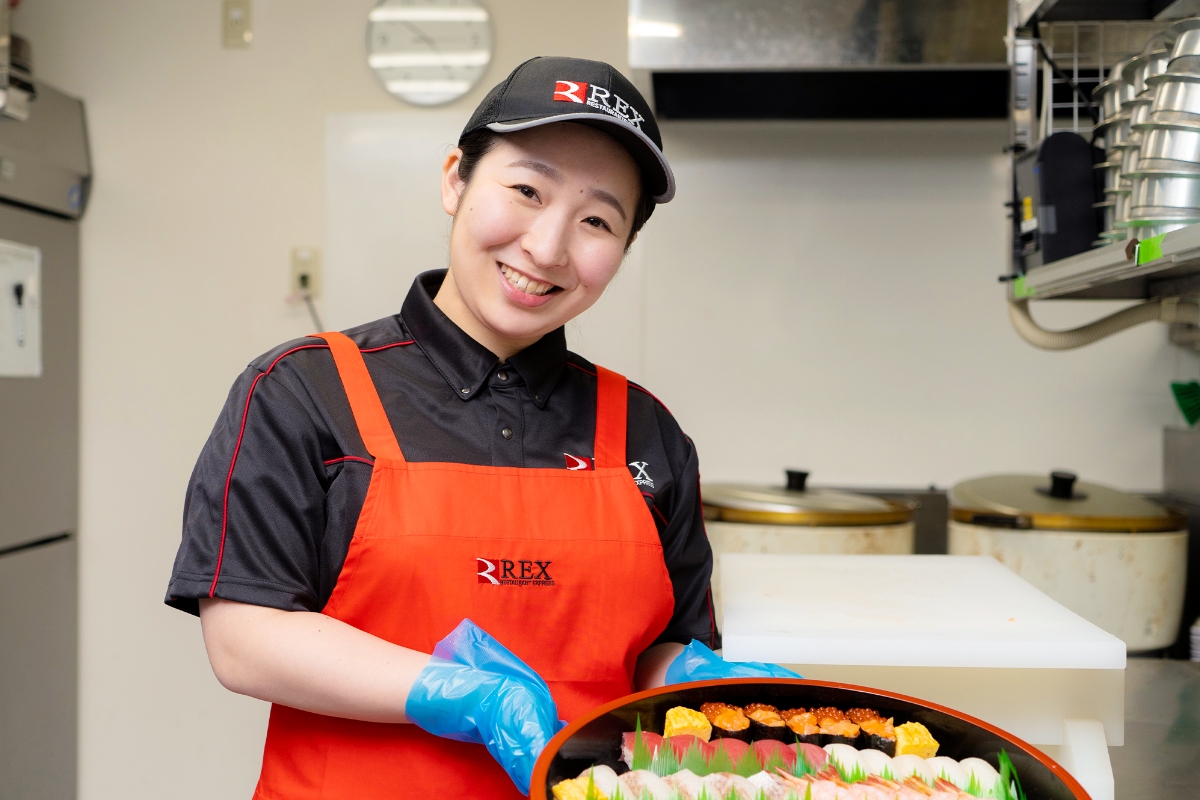 笑顔で調理した料理を見せるSさん