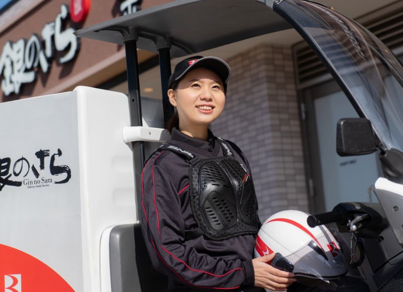 配達用車両のそばでヘルメットを持つSさん
